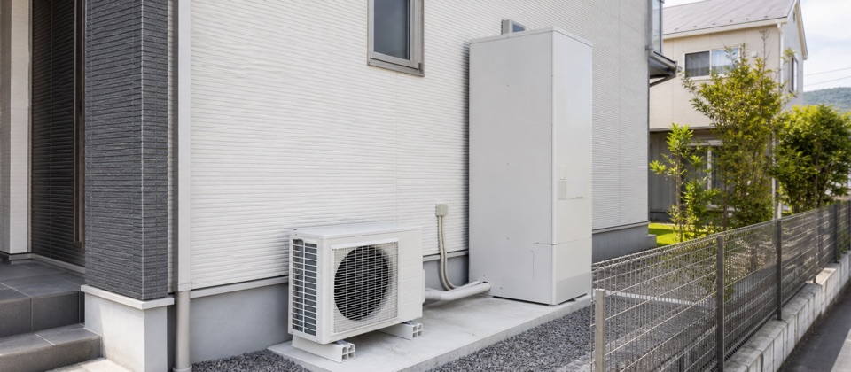 住宅の外壁沿いに設置されたエコキュートの貯湯タンクとヒートポンプユニット